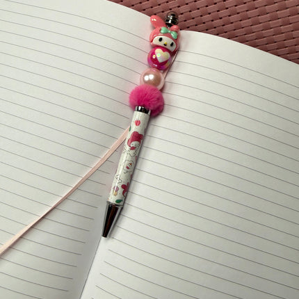 Pen with decorative charm on an open notebook
