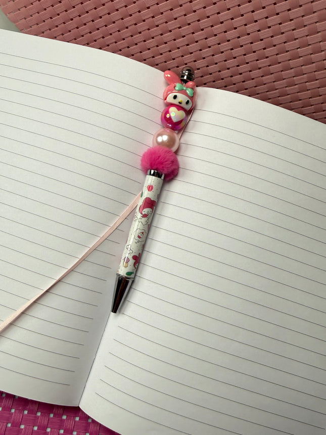 Pen with decorative charm on an open notebook