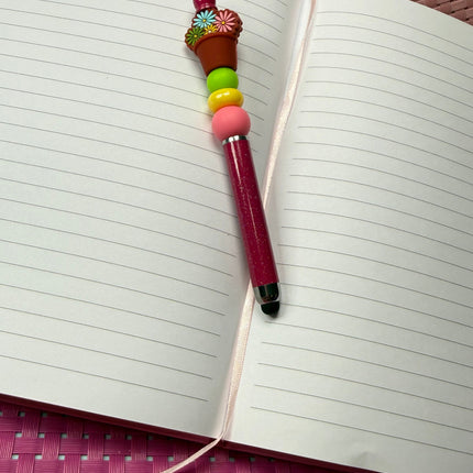 Stylus pen deep Maroon with shimmer featuring pink, yellow and green silicone beads with a focal of potted daisy flowers in multiple colors. 