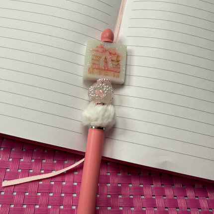 Pink Stylus pen with white fluffy spacer with pearl; rhinestone bead and pink spacer with a glittery white focal of stacked books with pink coquette bow. 