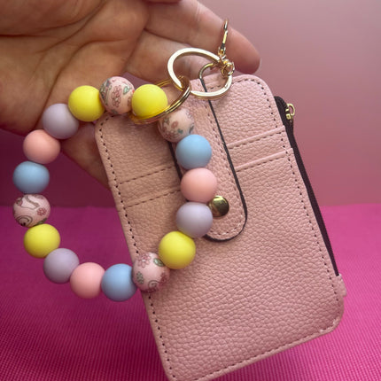 Pastel Smiley Wristlet Wallet Combo featuring a blush faux leather wallet with ID holder, zipper coin pouch, and pastel silicone beaded wristlet with retro smiley flower beads.