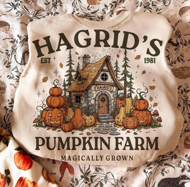 Cream sweatshirt with Hagrid’s Pumpkin Farm cottage design surrounded by pumpkins, jack-o’-lanterns and autumn leaves.