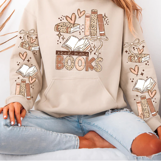 Person wearing a beige crewneck with book-themed designs and text.
