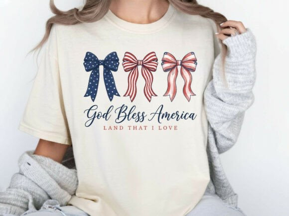 Person wearing a cream sweatshirt with 'God Bless America Land That I Love' text and three bow designs.
