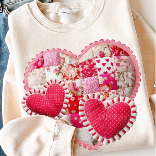 White sweater with pink heart-shaped patchwork design on a neutral background