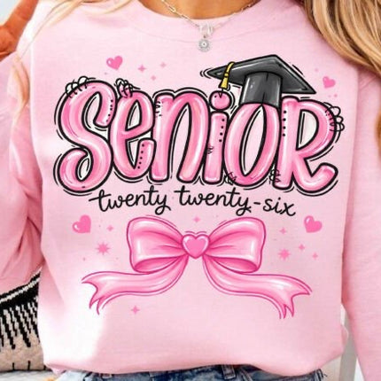 Pink sweatshirt with 'Senior twenty twenty-six' text and graduation cap design.