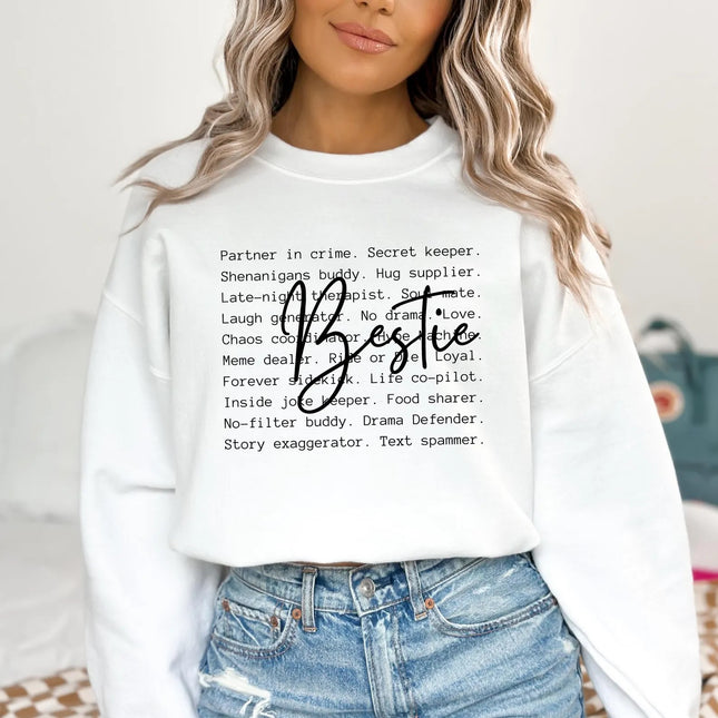 Person wearing a white sweatshirt with text and the word 'Bestie' on a neutral background
